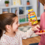 Mother giving L’il Critters Gummy Vites multivitamins to her smiling daughter at home during a healthy daily wellness routine.