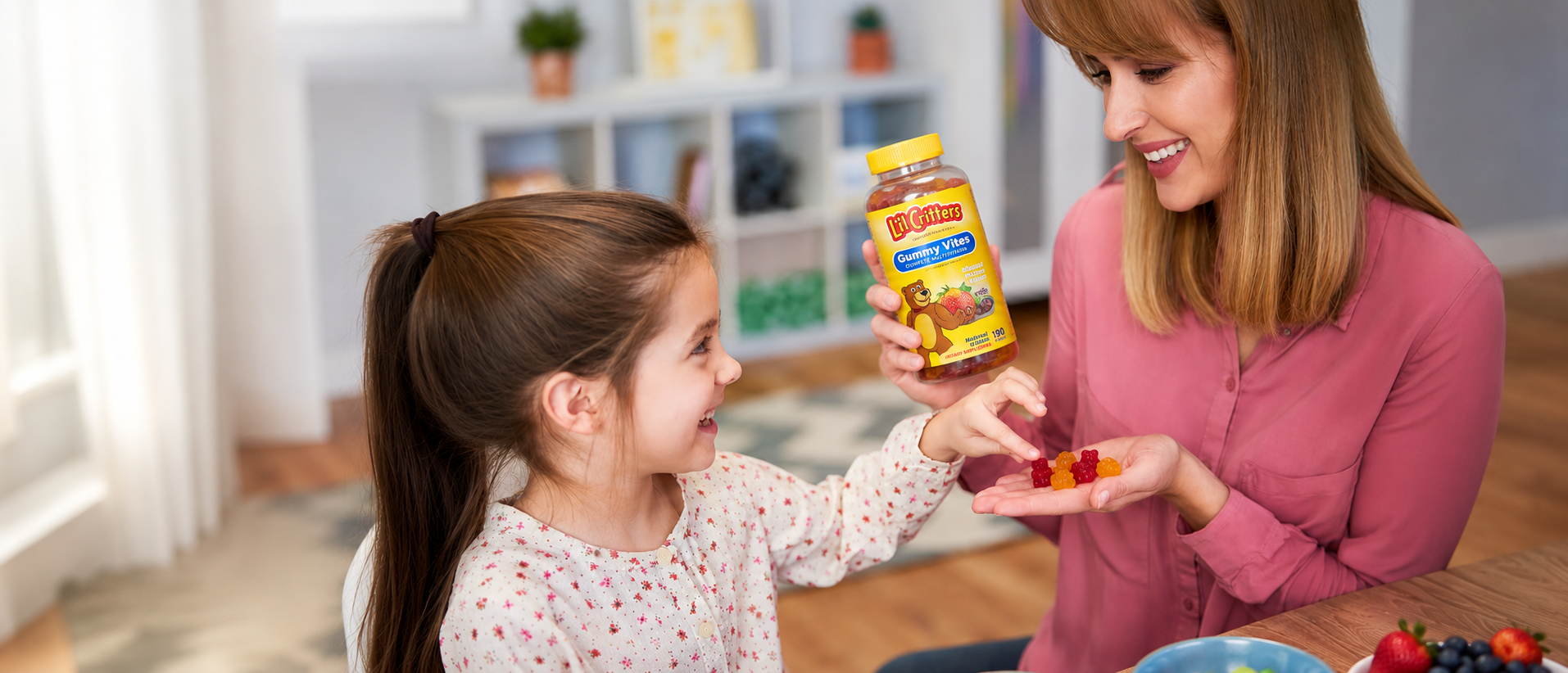 Mother giving L’il Critters Gummy Vites multivitamins to her smiling daughter at home during a healthy daily wellness routine.