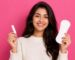 Woman holding a tampon and sanitary pad to compare menstrual hygiene products and period protection options.